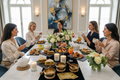 5 gourmet sandwiches with french pastries, teas, mocktails, luxurious tablescape with florals, sixtea candles, sound bowls, and tarot cards with dressed up people seated at the table in an elegant modern setting