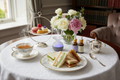Three gourmet finger sandwiches, pastry trio, tea, aromatherapy on a table setting with flowers